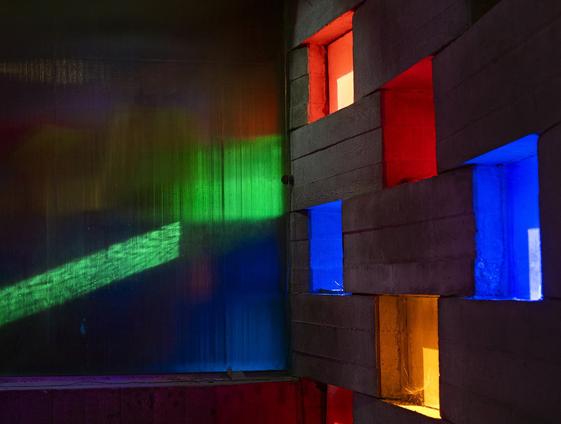 Image of light shining through green, blue, red and orange windows in the Meeting House